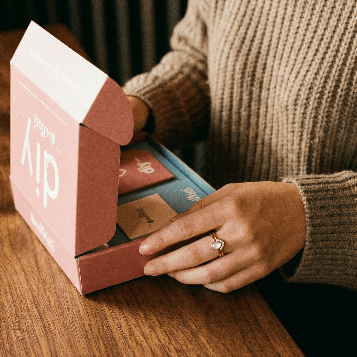 Kit DIY by MILKIES abierto sobre una mesa, con instrucciones y materiales incluidos para crear anillos de leche y otros recuerdos en casa de forma privada y sencilla.