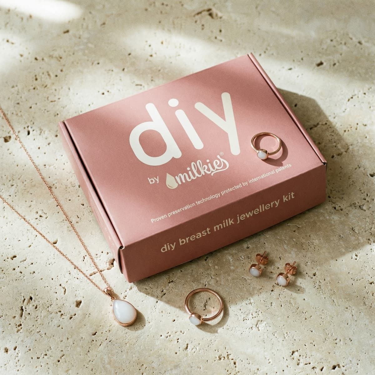 Kit DIY by MILKIES en caja rosa con collar, anillo y pendientes en tono oro rosa incluidos, un kit resina leche materna para crear joyería de recuerdo en casa.