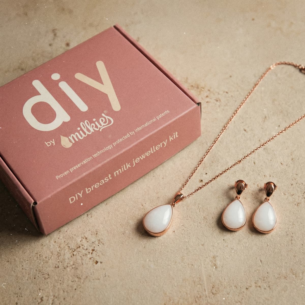 Kit DIY by MILKIES para crear joyería con leche materna, un regalo embarazada con caja rosa y set de collar y pendientes en tono oro rosa con piedra blanca.