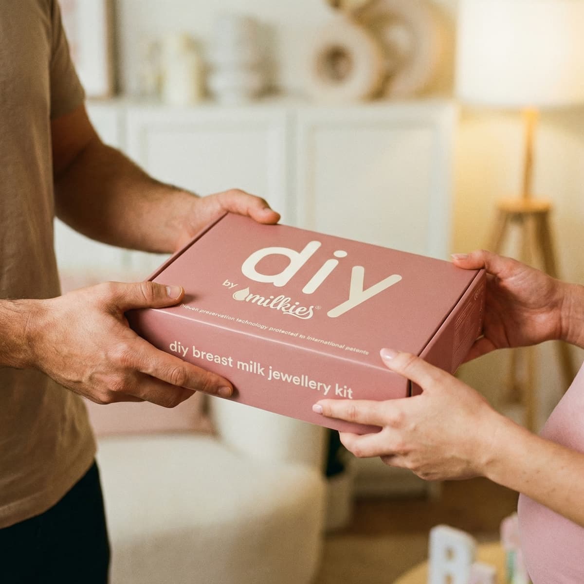 Personas entregando una caja rosa de DIY by MILKIES, un regalo lactancia en forma de kit DIY para crear joyería con leche materna en casa.