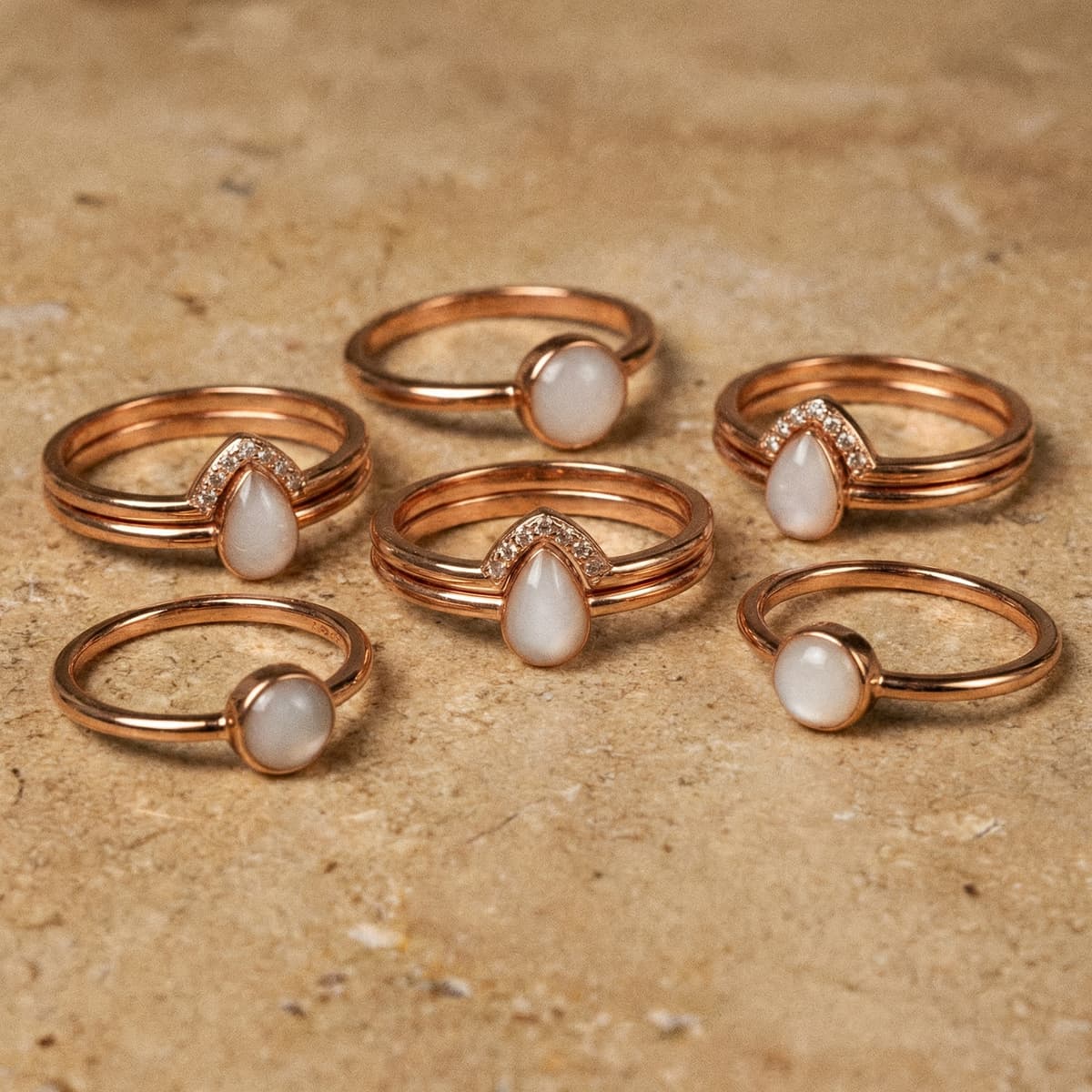 Conjunto de anillos finos en tono oro rosa con piedras blancas en forma de gota y redonda, ejemplo de kit creación anillo leche materna para hacer una joya recuerdo en casa.