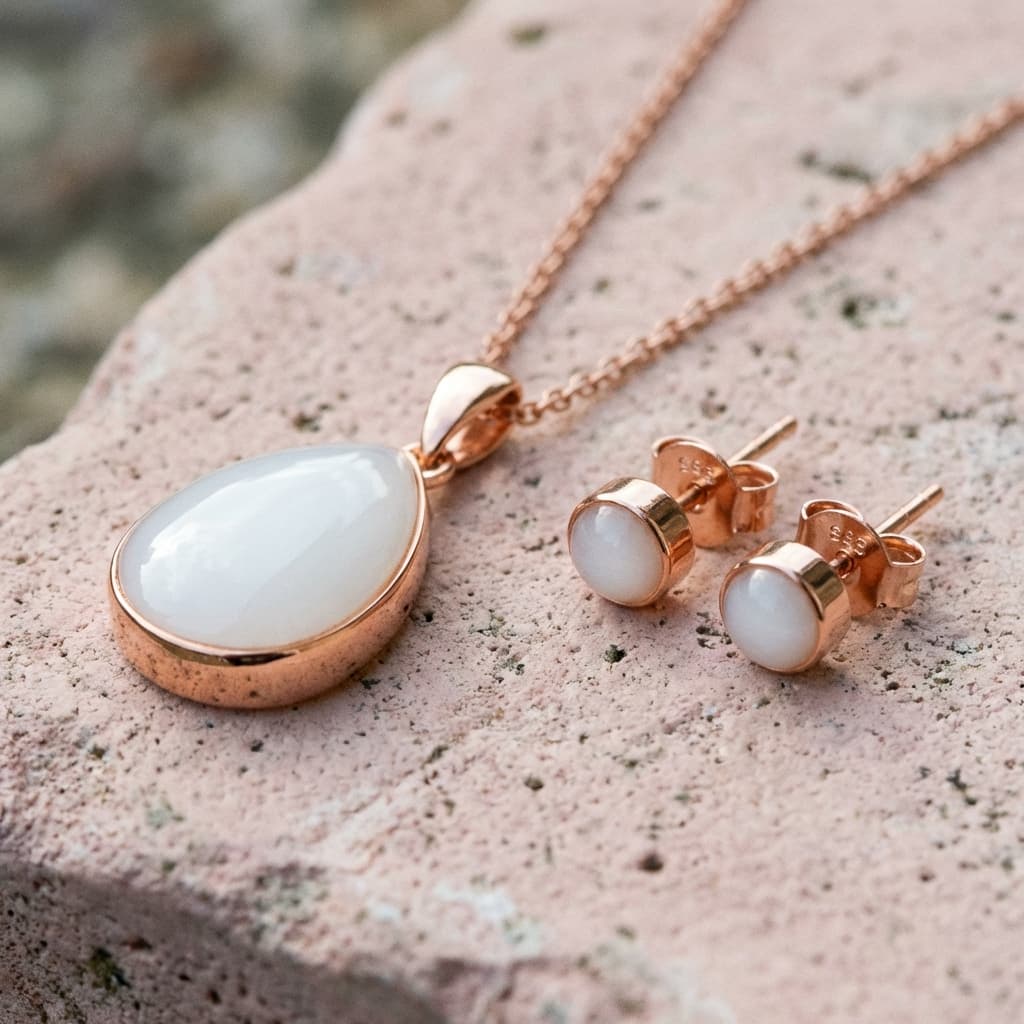 Conjunto de joyería en tono oro rosa con colgante ovalado y pendientes a juego con piedra blanca, creado con un kit manualidad lactancia para conservar leche materna en resina como recuerdo.